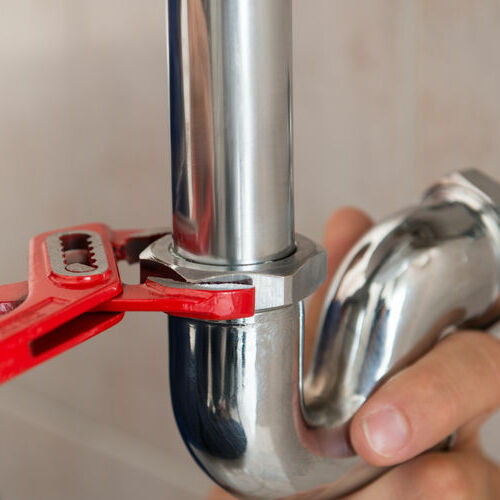 A plumber adjusts a pipe.